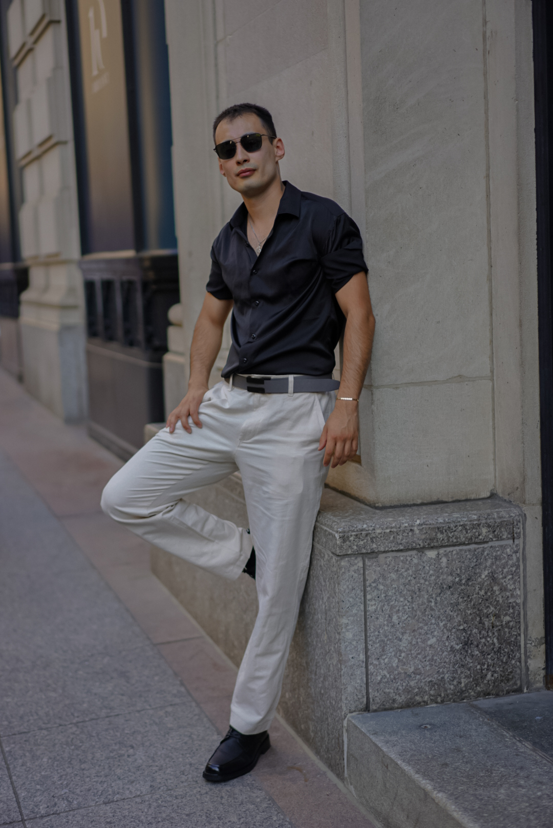 Groom in refined tailoring leaning against a column in Manhattan